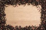 Peppercorn spice frame on wood with assorted black, red and white whole dried peppercorns for food themed concepts with central copy space