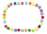 Colorful oval frame of wooden toy building blocks in the colors of the rainbow arranged on white with copy space