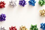 Border of colorful shiny metallic ribbon bows for packaging gifts around a central white copy space for a festive celebration