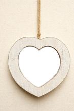 Rustic off white wooden heart shaped picture frame hanging by a cord on a cream colored background with central copy space for your love or romance themed artwork