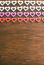 Colorful rows of cut out modern shaped hearts on wood with copy space below for your romantic or love themed concepts