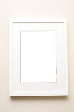 Blank picture frame in white over wall with copy space for portrait or mirrored reflection