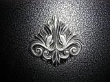 Acanthus leaf decoration on a fireplace in raised relief against a textured pitted background, central highlight on the decoration