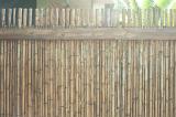 Tightly packed stacks of bamboo as fence in tropical climate during daytime. Includes copy space.