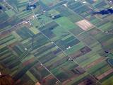 Aerial view of cultivated farmland in flat open countryside with a scattering of farm houses
