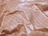 Extreme close up of crumpled waxy brown paper with highlights from overhead light source