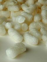 Overhead extreme close up view of packing peanuts made from soft plastic material with one lone piece set aside