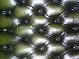 Tightly cropped close up on dark green sofa back cushion with leather type upholstery