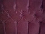 Tightly cropped close up on dark red sofa back cushion with felt type upholstery