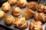 Delicious small individual light puffy Yorkshire Puddings made from batter in a baking tray ready to be served as an accompaniment to roast beef