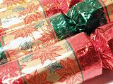 Christmas crackers with decorative poinsettias on the shiny gold wrapper viewed close up ready for a festive Xmas table