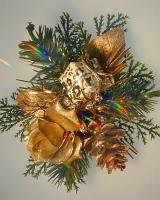 Gold Christmas decoration with pine foliage, a rose, cone and gift over a neutral beige background