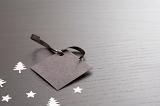 a blank christmas gift tag on dark background with silver trees and stars