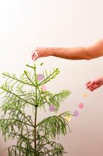 decorating a christmas tree, a plain tree with a man holding paper decorations
