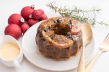 traditional round, christmas fruit pudding on a plate with brandy custard