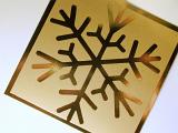 Close up of shiny golden snowflake icon on square piece of paper on white background