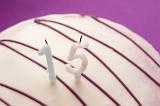 White Cake Drizzled with Chocolate Icing Topped with Unlit Candles for 15th Birthday Celebration, Teenagers Birthday on Purple Background