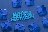 a blue background with metallic blue happy birthday shape and presents