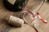Celebration new years with champagne, close-up view of cork on wooden table near glass and wine bottle