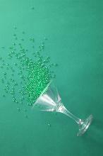 Colorful green cocktail background with copy space conceptual of a party with sprinkled beads spilling from an upturned martini glass