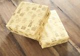 Two Birthday Gifts Wrapped in Matching Patterned Yellow Paper Stacked on Wooden Surface