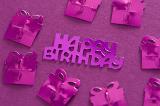 Fuchsia Gift Shaped Foil Confetti Arranged Around Happy Birthday Message on Fuchsia Background