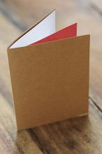 Close Up of Blank Greeting Card or Invitation Made from Natural Paper on Outside and White and Red Paper Inside on Wooden Surface
