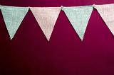 Party bunting textile triangular flags on a string in close-up on dark red wall, as decoration background design