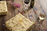 Wrapped Birthday Gift on Wooden Surface with Ribbons, Streamers, Confetti and Alcoholic Drinks