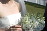 a wedding reception, the bride holds her bouquet of summer stocks and a glass of champagne