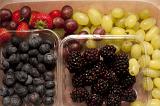 Overhead view of assorted fresh berries and grapes in containers including strawberries, blueberries and blackberries