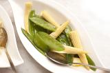 Side serving of tasty vegetables in an individual dish with mangetout or sugar snap peas and baby corncobs