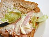 Preparing a sandwich for lunch with thinly sliced ham and lettuce on brown bread, closeup view