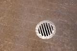 water running onto a shower drain hole and tiles