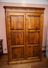 Old vintage wooden wardrobe or armoire with closed doors standing in a bedroom, close up view