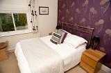 Stylish double bed in a modern bedroom with neutral decor , a metal headboard and wallpaper