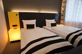 Funky modern black and white bedroom interior with twin beds and illuminated bedside tables