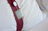 Hotel bedroom pillow with a decorative band tied around it with an attached tag, close up view conceptual of the hospitality industry