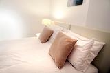 Close up of a modern bedset with neutral decor in tones of brown, beige and white illuminated by bedside lamps