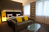 Modern empty bedroom suite with a double bed, couch and table and illuminated bedside table with neutral decor and yellow highlights