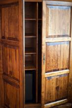 Old rustic wooden wardrobe with the doors ajar to reveal empty shelves inside,close up view