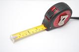 Retractable builders tape measure marked in both centimeters and inches for measuring the length of an object, high angle on white