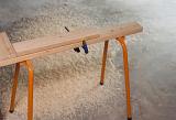 Carpenters horse or narrow work bench allowing easy access to planks of wood on both sides while clamped, surrounded by wood shavings