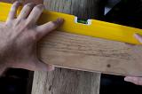 Carpenter using a spirit level to adjust the horizontal angle on a plank of wood, close up of his hand and the bubble in the level