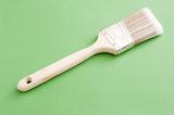 Painters brush for interior decorating with a wooden handle lying diagonally on a green background with copyspace