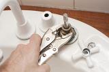 Man using a mole grip wrench to dismantle a tap or faucet to replace a faulty washer in a DIY and renovation concept