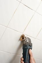 removing the grout from bathroom tiles with a diy renovator tool