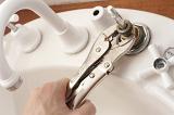 Man repairing a faucet with a mole grip pliers replacing the washer having dismantled the top of the fitting in a DIY concept