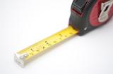 Builders retractable tape measure with centimeters and inches on a white background with part of the tape extended to show the two scales