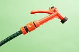 Orange plastic garden spray nozzle on the end of a hosepipe for watering delicate seedlings and seed beds